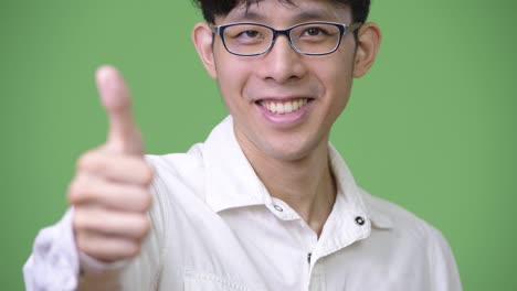 young asian businessman giving thumbs up to camera