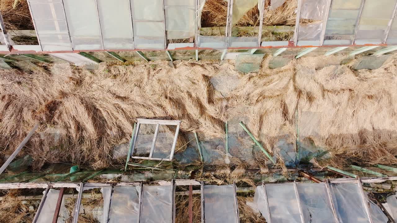 Aerial close view of torn film and glass textures on broken greenhouse rooftops
