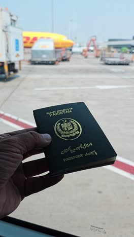 hand holding a pakistani passport at an airport