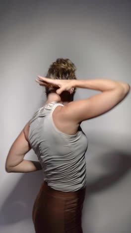 a skilled female dancer gracefully performs expressive movements with elegance and artistry, set on a simple gray background