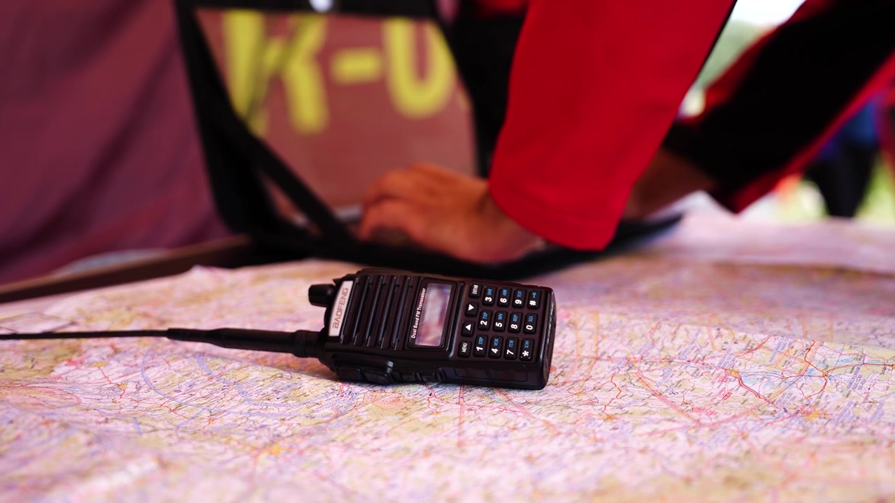 Handheld transceiver on paper map and person hands in background, Czechia