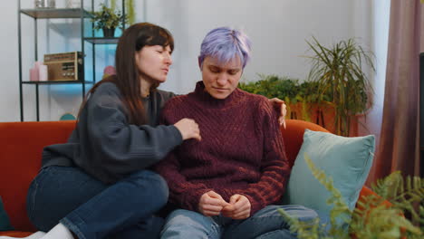 Two lesbian women family couple at home, woman tries to calm sympathize and hug her wife, compassion