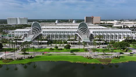 aerial view of a large modern convention center with palm trees and lake