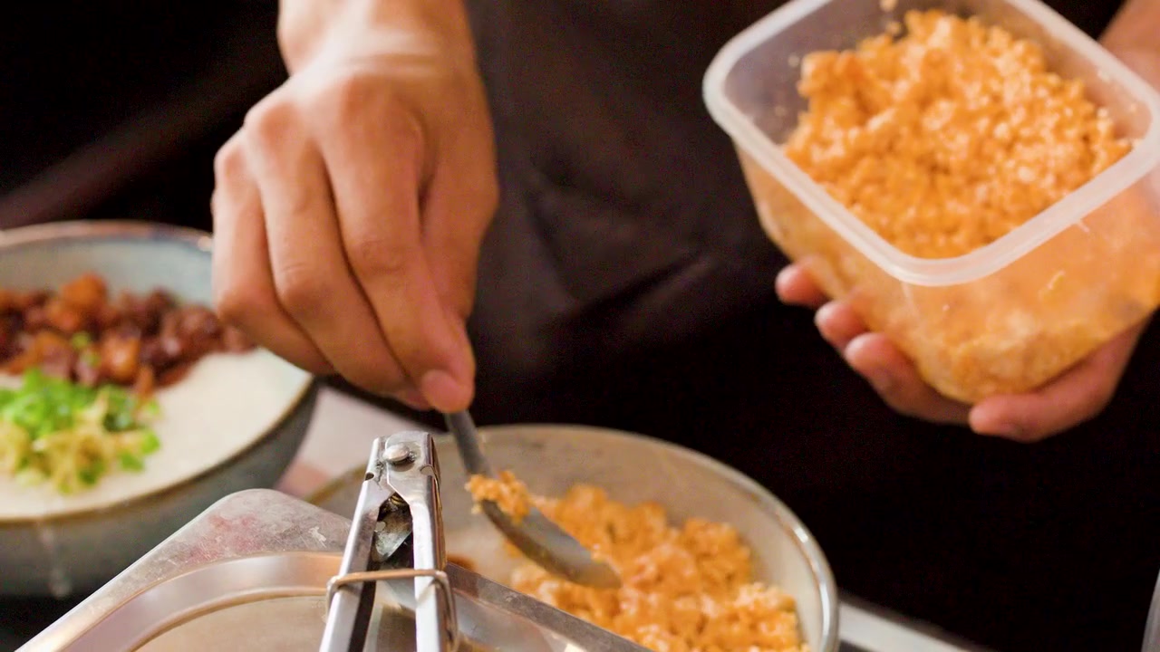 Chef che aggiunge guarnizioni croccanti a una ciotola di congee