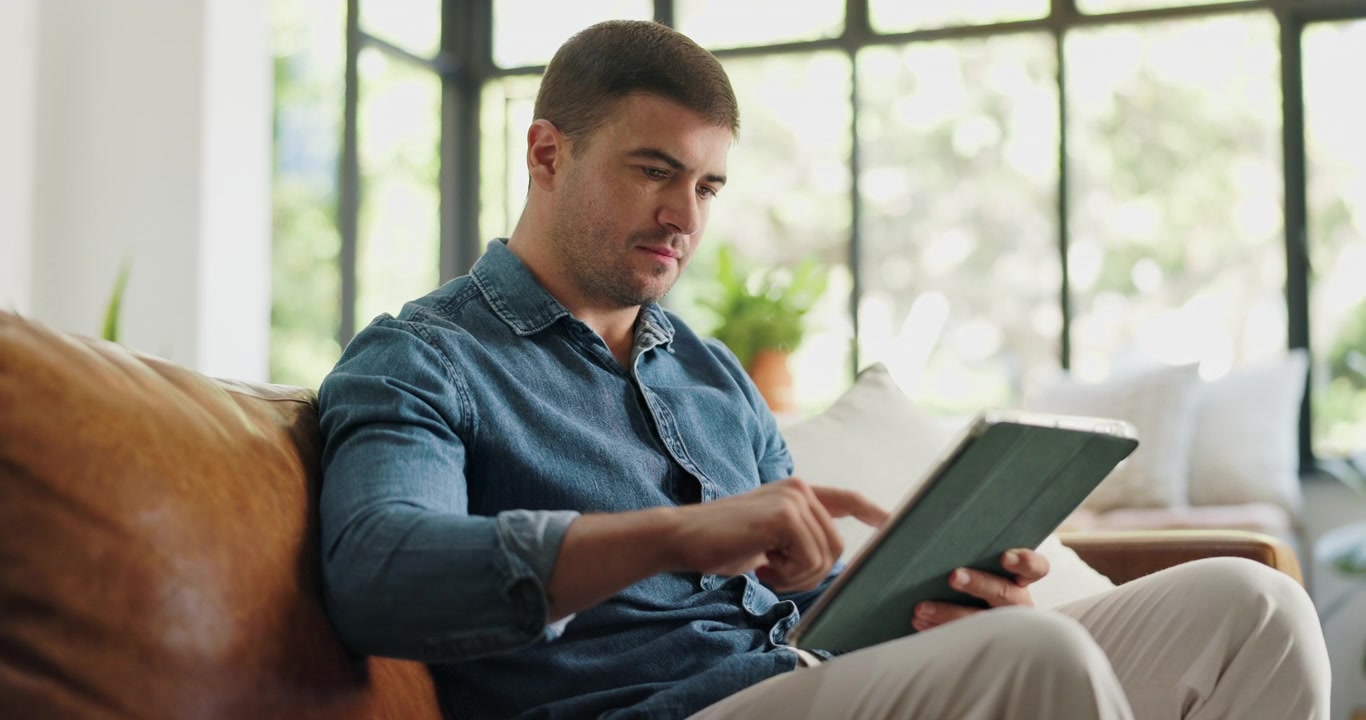 Man Using Digital Tablet While Sitting on Leather Sofa