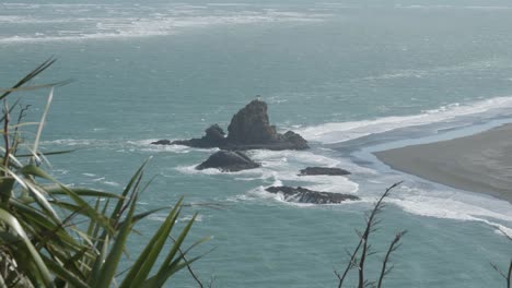 rocks and lighthouse on whatipu beach, omanawanui, new zealand