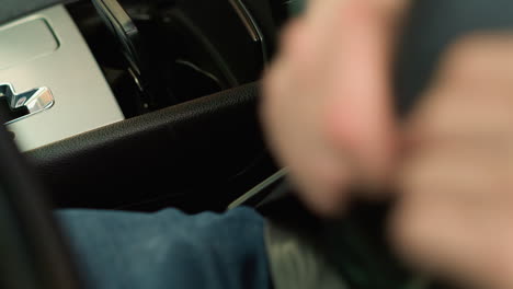 close-up shot of a person in a car fastening their seat belt, focusing on the hand pulling the belt across their lap. the shot captures the importance of safety and routine before driving