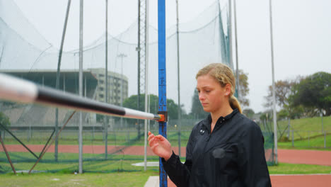 front view of caucasian female athlete checking high jump bar at sports venue 4k