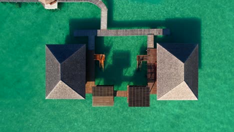 top down view of a private villa in the middle of the sea with a wooden pier at leebong island, belitung, indonesia