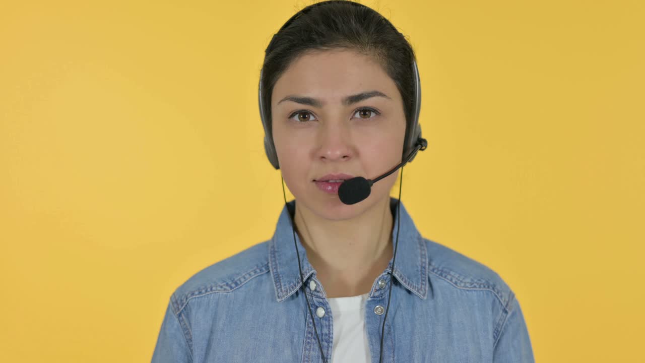 Young Indian Woman with Headset Looking at Camera, Yellow Background
