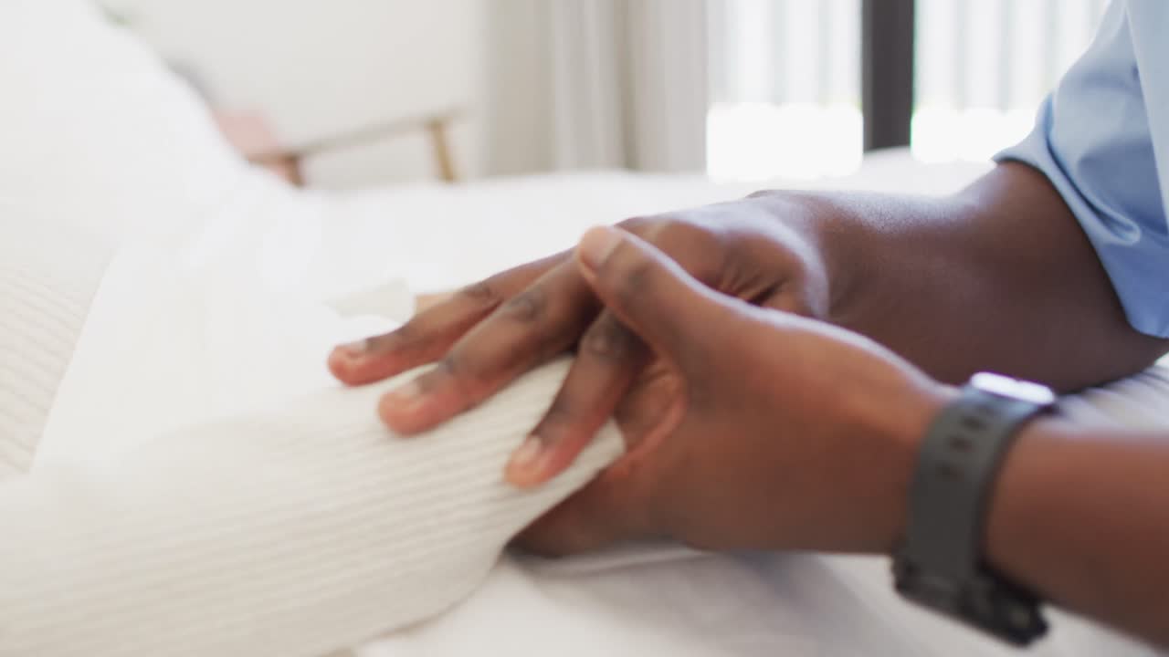 video de las manos de un médico afroamericano sosteniendo a una mujer caucásica mayor