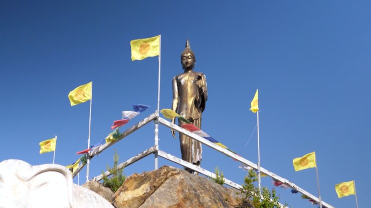 Bandiere di preghiera che sventolano con una statua di Buddha sullo sfondo, tempio sacro, inquadratura media.