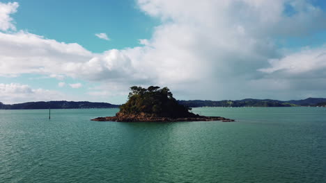 small island in bay of islands new zealand with several trees on sunny day, slow