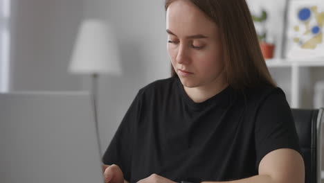 self-education-by-internet-young-woman-is-using-laptop-making-notes-in-notebook-portrait-of-woman-in-living-room-e-learning-of-students