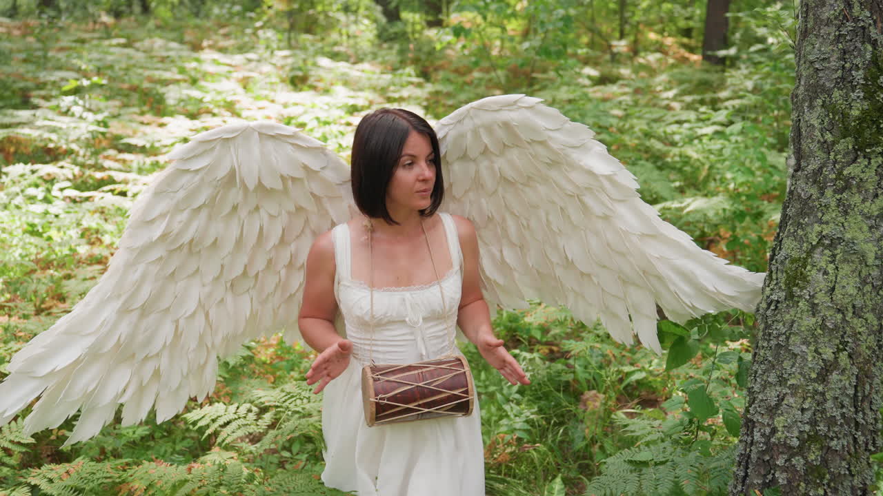 Beloved of Eros with graceful white wings walking slowly through forest, softly beating small kalimba drum surrounded by sunlight and lush greenery, expressing purity