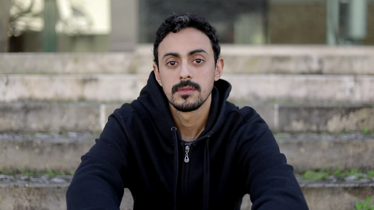 un joven guapo sentado en la calle