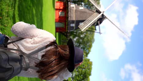 woman with hat and backpack looking at historic windmill in kastellet, denmark