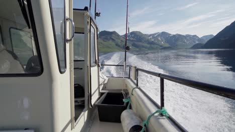 trail of foamy waves left at the sea from traveling fishing boat with ridges at background in norway