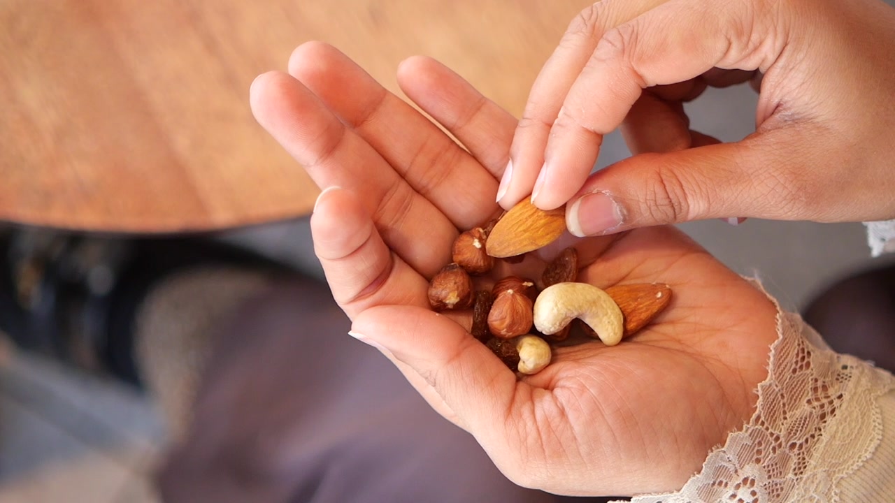 Close-up of a Hand Picking Mixed Nuts and Dried Fruits