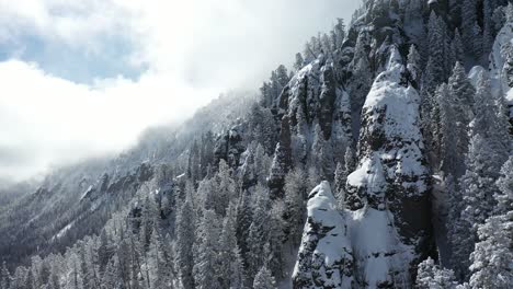 Mountain-forest-in-snowy-winter-landscape-drone-aerial-view,-snowcapped-conifers-and-steep-hills,-drone-shot