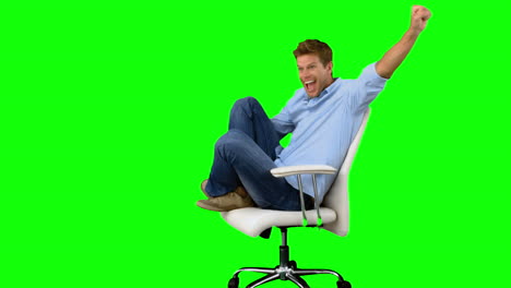 Smiling-man-cheering-and-turning-on-swivel-chair-on-green-screen