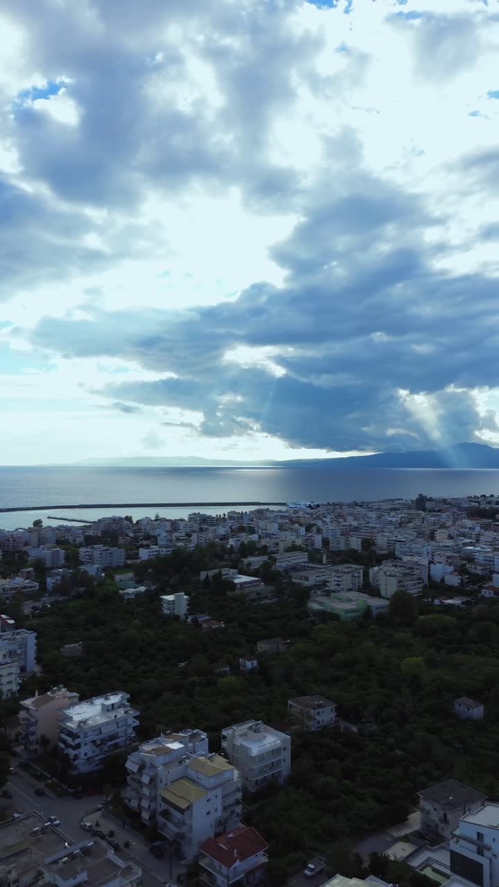 Aerial, vertical high angle panoramic view, transition from Messinian gulf to cityscape of Kalamata, Messinia, Peloponnese , Greece on a cloudy autumn day. Right pan drone movement 4K