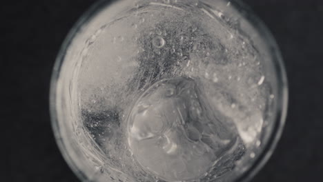 las manos de primer plano lanzan un cubo de hielo en un vaso con agua gaseosa. hacer concepto de cóctel