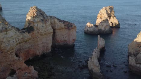 acantilados de piedra caliza dorada y pilas de rocas a lo largo de la costa portuguesa cerca de lagos, ángulo alto