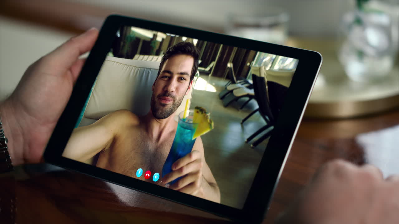 Uomo in videochiamata a bordo piscina con un cocktail