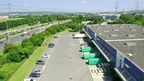 aerial moving shot of a logistics warehouse huged by a highway and power lines close to paris, france