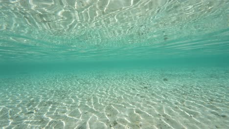 Split-shot,-camera-emerges,-half-above,-half-below-water-of-a-tropical-beach-in-Fakarva,-second-biggest-atoll-in-French-Polynesia-in-the-south-pacific-ocean-in-Slow-motion