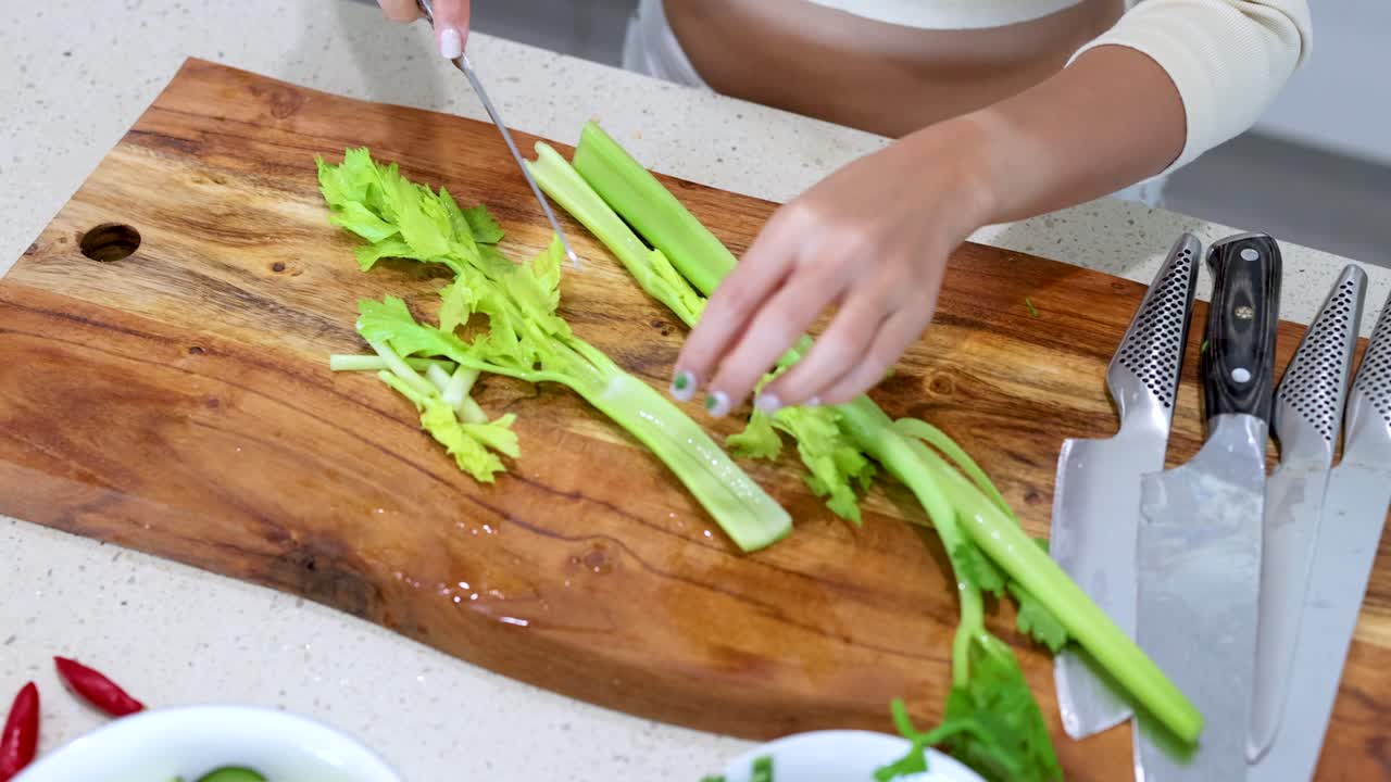 Woman cutting celery on a wooden chopping board