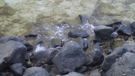 gentle waves surrounding the black rocks in coastal environment of fiji