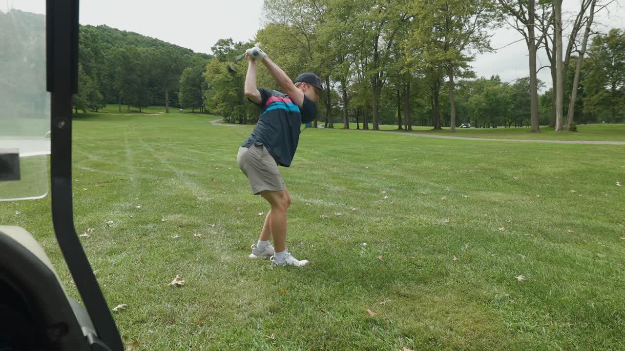Golfer takes a clean shot from the fairway on a scenic, green golf course