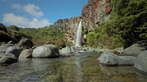 fresh water creek with boulders and waterfall in background, low angle shot