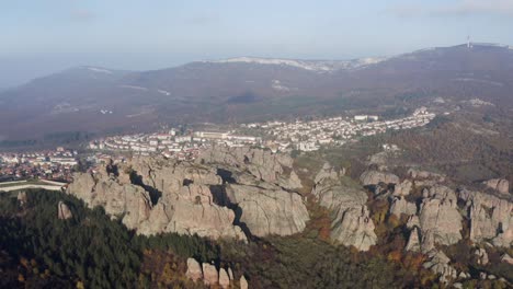 Straffe-aerial-drone-shot-panning-from-right-to-left,-showing-a-panoramic-view-of-the-Belogradchik-natural-rock-formations-with-the-Balkan-mountains-in-the-backgorund,-in-Vidin-province,-Bulgaria