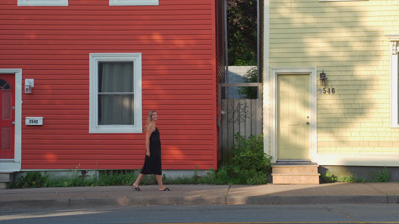 primer plano de casas coloridas con una mujer caminando frente a ellas por la mañana en halifax, nueva escocia