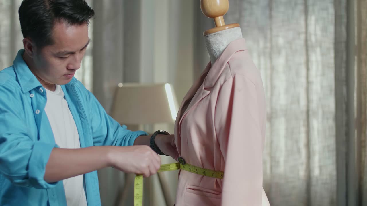 스튜디오에서 옷을 디자인하는 동안 마네킨에 재을 측정하는 바느질 기계와 함께 아시아 남성 디자이너의 클로즈업