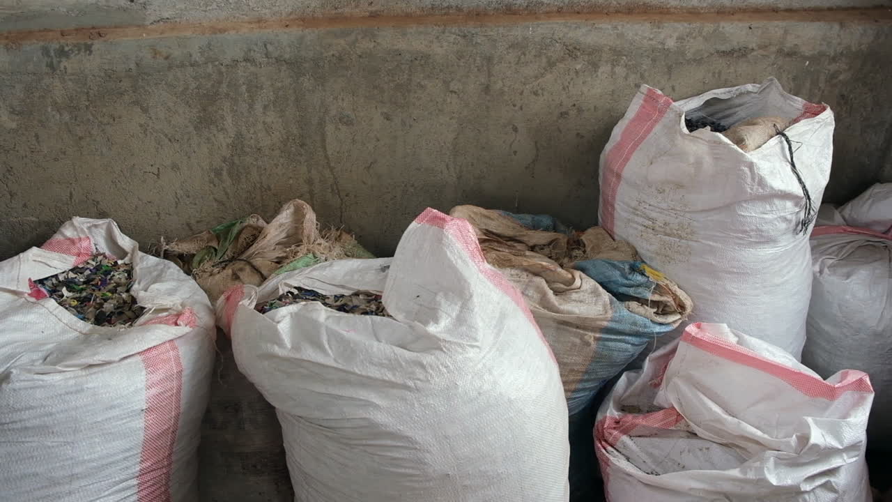 Large bags filled with recycled materials in a concrete storage area