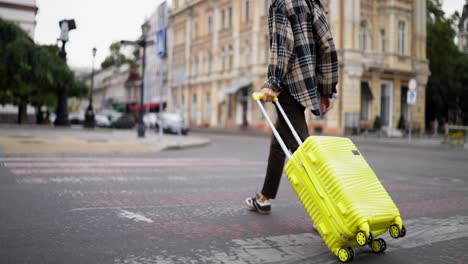 person walking across the street with a yellow suitcase