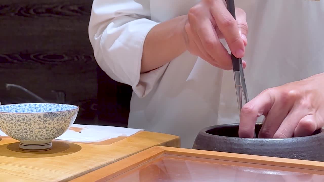 A chef expertly uses chopsticks to prepare an octopus dish, showcasing culinary skill and attention to detail.