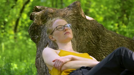 close up shot of young woman lying and relaxing on the tree branch