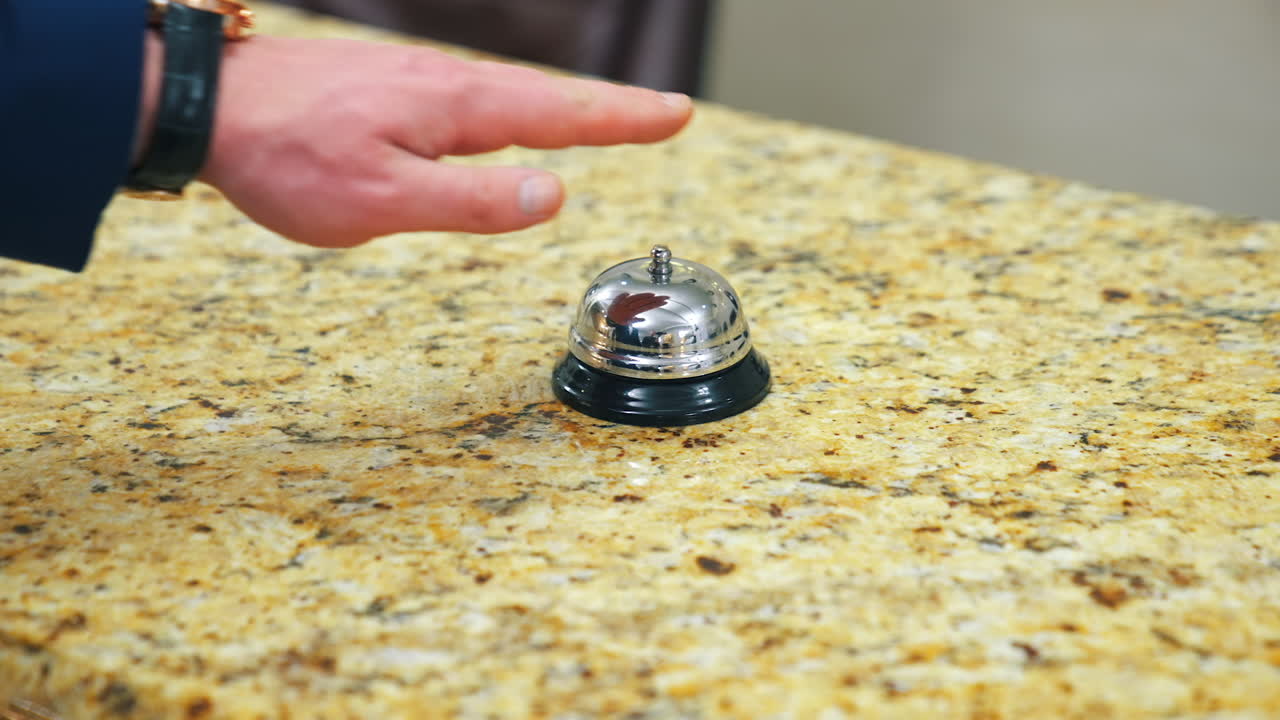 Bell on reception at the hotel to call the administrator. Beautiful blurred background. The hand of the man who presses the call. Concept for hotels.