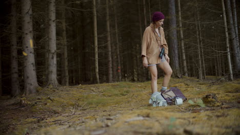 Woman-with-binoculars-keeping-backpack-on-ground