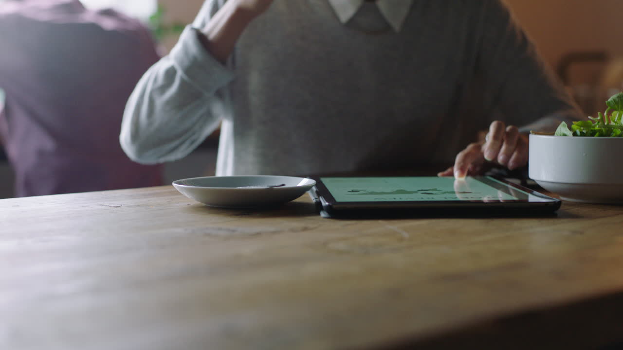 cerca de las manos de una mujer de negocios usando una tableta digital en un café bebiendo café leyendo un documento de correo electrónico en un dispositivo móvil con pantalla táctil disfrutando de la tecnología portátil en un restaurante ocupado