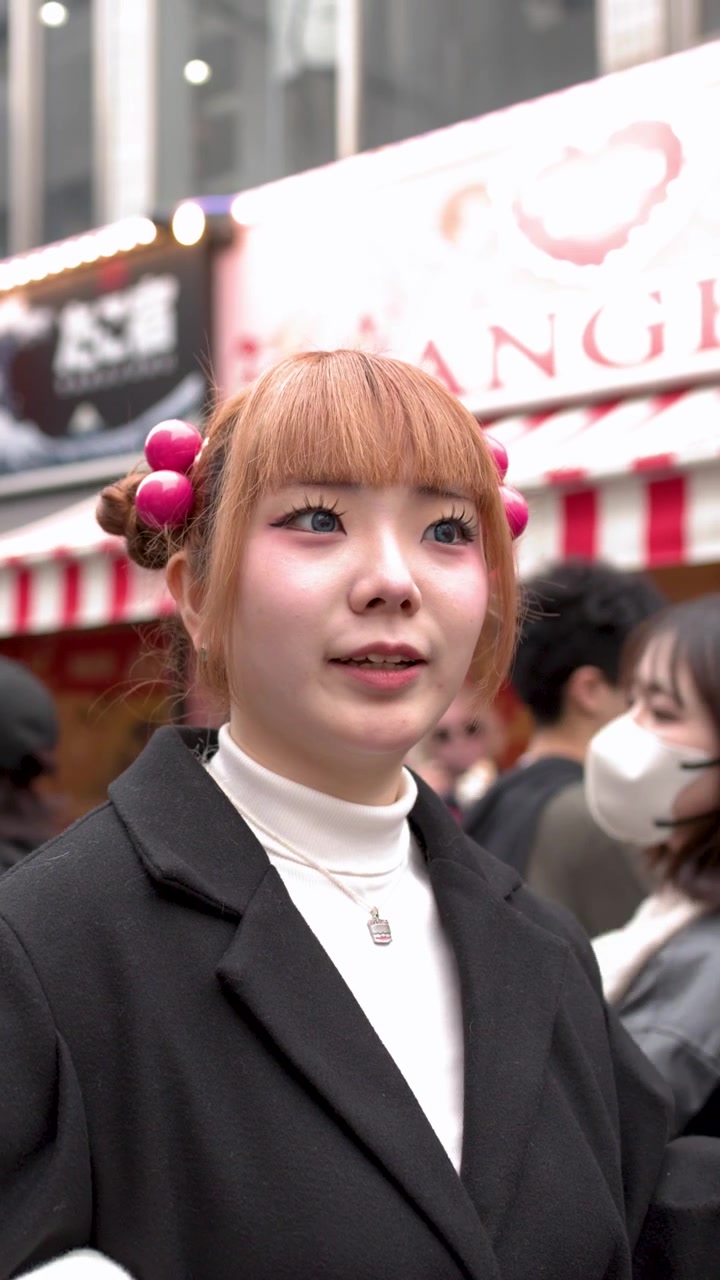 Primo piano di una donna giapponese elegante che parla in una trafficata strada di Harajuku a Tokyo.