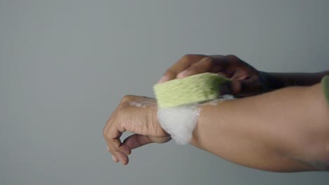 person washing arm with sponge and soap