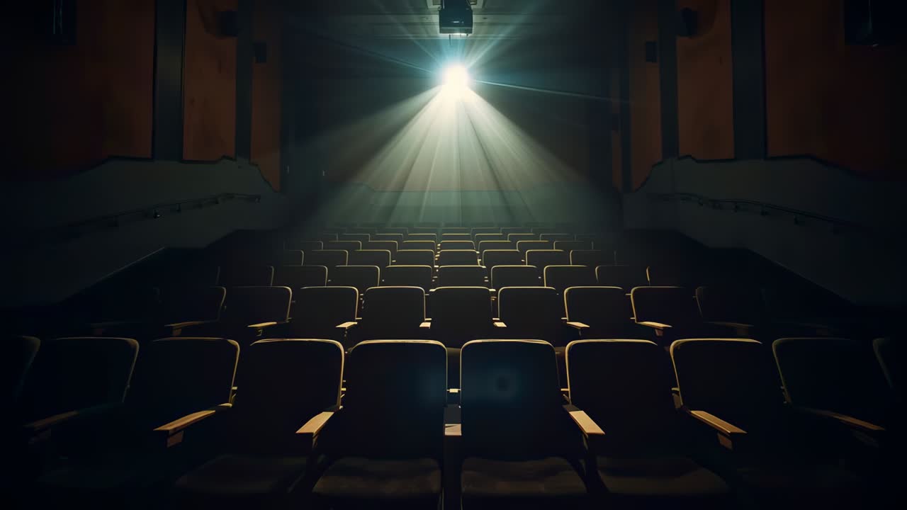 Accensione del proiettore montato a soffitto che proietta un fascio di luce attraverso la sala di un cinema, illuminando le poltrone vuote