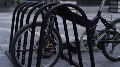 Nahaufnahme-Eines-Schwarzen-Fahrrad-Elektrorollers,-Der-Auf-Einem-Gemeinschaftsparkplatz-Auf-Dem-Bürgersteig-Steht.