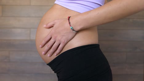 pregnant woman in third trimester, touches gently belly, static side shot